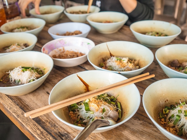 Veel kleine kommen Thaise noodle geserveerd op tafel.