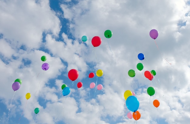 Veel kleurrijke ballonnen vliegen op bewolkte blauwe lucht