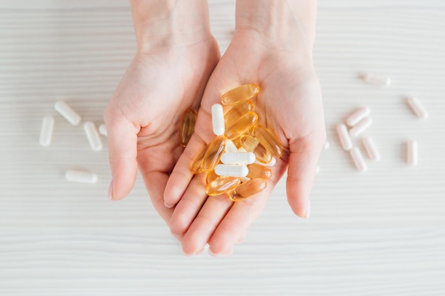 Veel kleurrijke capsules van tabletten, vitamines, voedingssupplementen in de hand op een witte tafel close-up. Tonen.