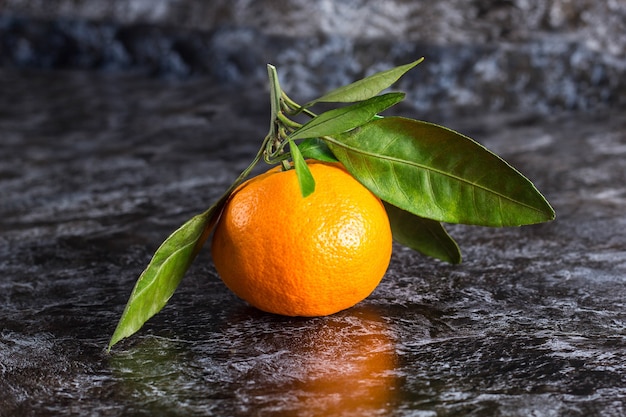 Veel oranje mandarijnen met groene bladeren op donkere achtergrond