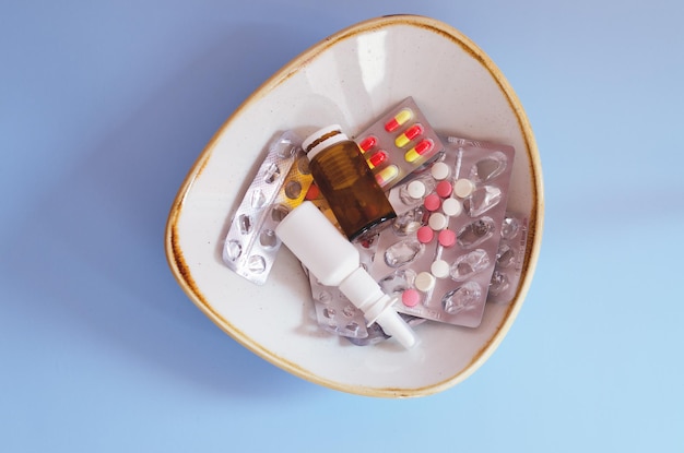 Veel pillen, neusdruppels, pakjes en blaren, pillen liggen in een bord op tafel. Gezondheidszorg