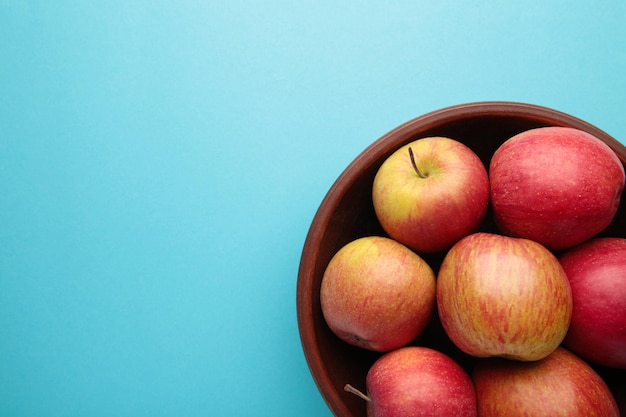 Veel rode appels in ronde kom op blauwe achtergrond Verticale foto