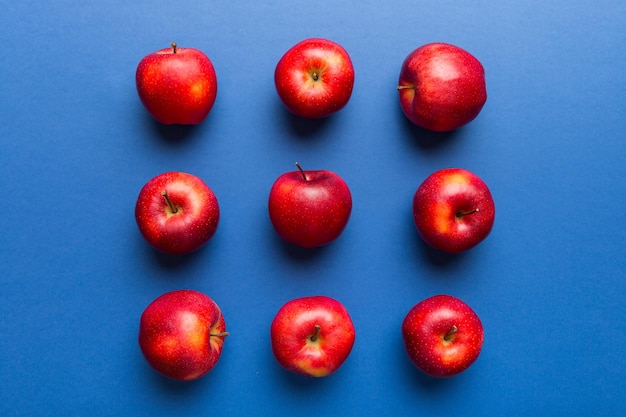 Veel rode appels op gekleurde achtergrond, bovenaanzicht. Herfstpatroon met verse appel boven uitzicht