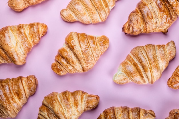 Veel vers gebakken croissants op een roze achtergrond. Achtergrond van croissants