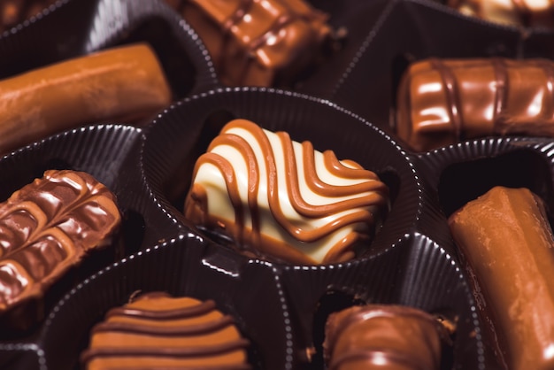 Veel verschillende chocolaatjes op witte houten achtergrond