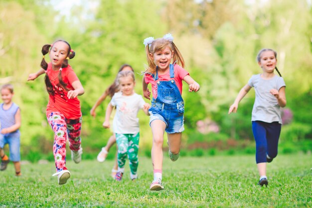 Veel verschillende kinderen, jongens en meisjes lopen in het park op zonnige zomerdag in casual kleding