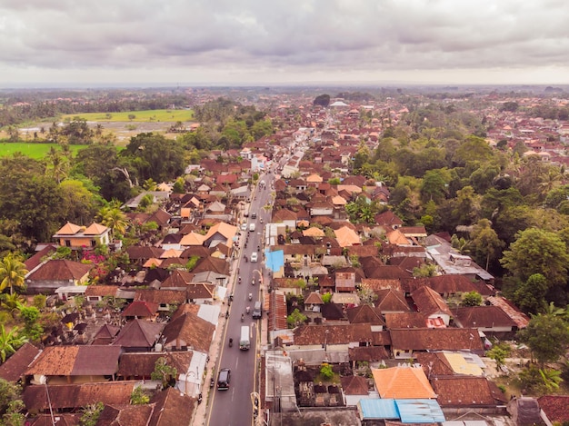 Veel villa's met bruinoranje dakspanen tussen tropische bomen op de hemelachtergrond in Ubud op Bali Zon schijnt op hen Horizontale luchtfoto