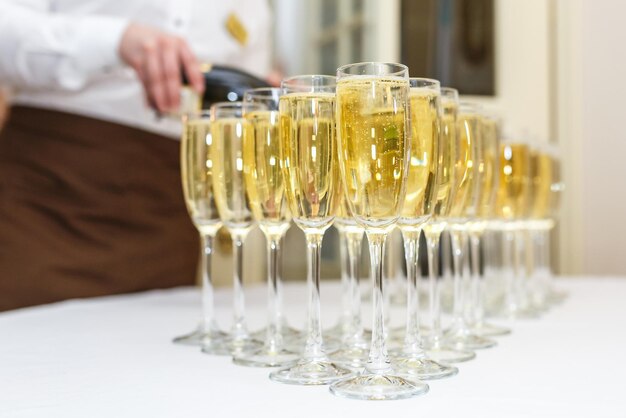 Veel wazige glazen met champagne op de feesttafel van de receptie op lichte achtergrond