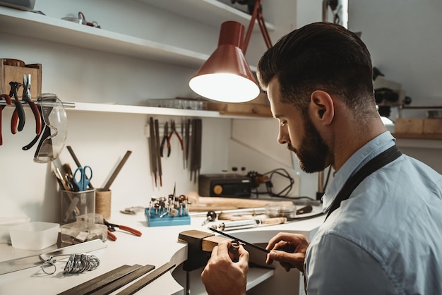 Veel werk in de werkplaats close-up van een jonge mannelijke juwelier aan het werk