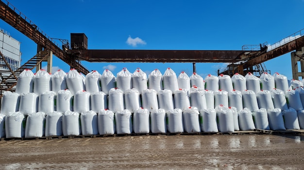 Veel witte big bags met chemische meststoffen in een magazijn buiten stapel zakken op een rij