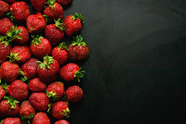 Veel zoete aardbeien ligt op een zwarte achtergrond