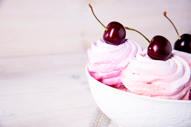 Veel zoete roze kersencakes in een witte plaat op hout