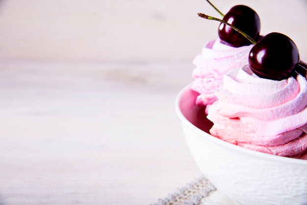 Veel zoete roze kersencakes in een witte plaat op hout