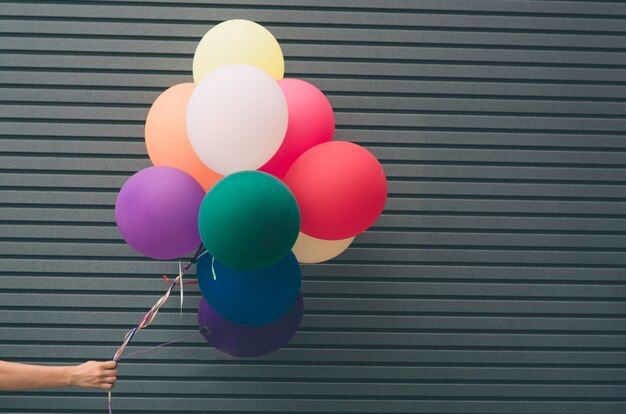 Veelkleurige ballonnen in de buurt van grijze muur