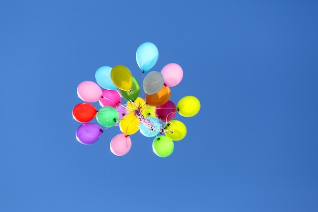 Veelkleurige ballonnen vliegen in de blauwe lucht
