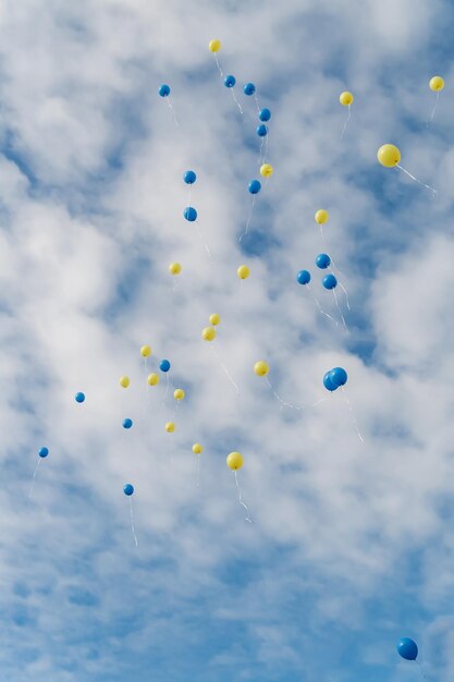 Foto veelkleurige ballonnen vliegen in heldere blauwe lucht met wolken