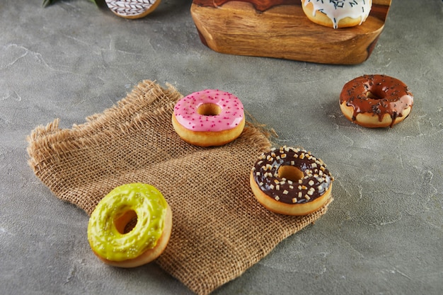 Veelkleurige donuts met glazuur en hagelslag met bloemen op een grijze achtergrond.