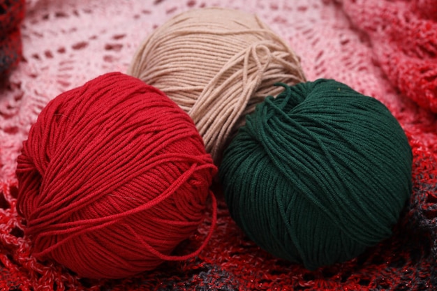 Veelkleurige drie bollen wol liggen op een gebreid tafelkleed Foto van hoge kwaliteit