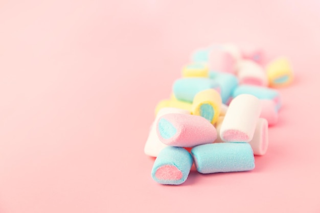 Veelkleurige gekleurde levendige marshmallows op een roze achtergrond het concept van de kindertijd