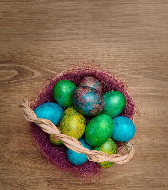 Foto veelkleurige geverfde paaseieren in een mand op een houten bovenaanzicht als achtergrond