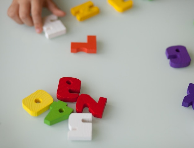 Veelkleurige houten letters en cijfers en kinderhand. Grijze achtergrond