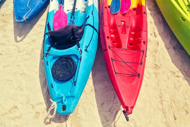 Veelkleurige kajaks met peddels op het zand bij de zee Bovenaanzicht