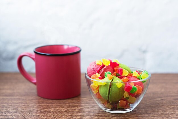 Veelkleurige koekjes in de vorm van noten met gevulde room en gekonfijt fruit en kopje koffie op tafel op lichte rug