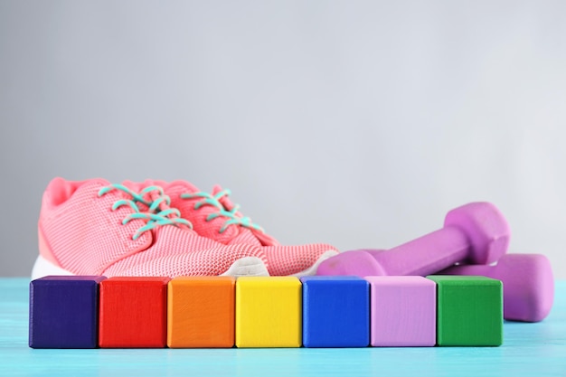Veelkleurige kubussen met ruimte voor tekst joggingschoenen en halters op grijze achtergrond