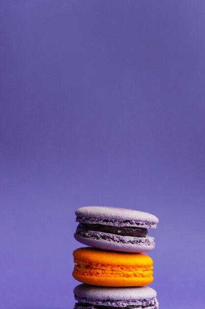 Veelkleurige macarons op een paarse achtergrond. Frans dessert voor Halloween. Amandelmeel gebakken goederen.