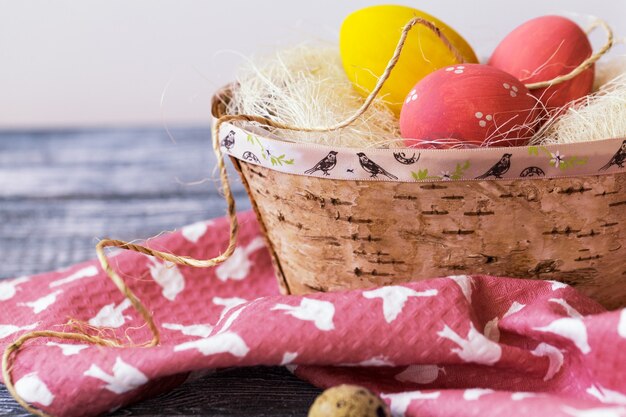 Veelkleurige paaseieren in een doos van berkenschors, servet op een houten