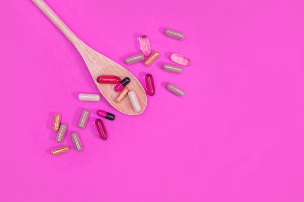 Veelkleurige pillen en capsules op een roze achtergrond