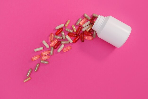 Veelkleurige pillen en capsules op een roze achtergrond