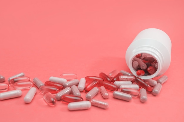 Veelkleurige pillen en capsules op een roze achtergrond