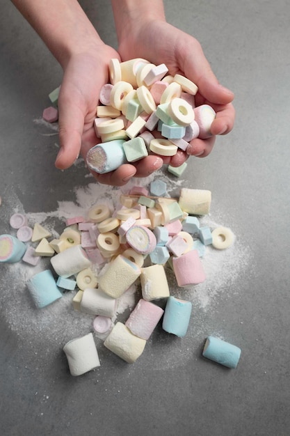 Veelkleurige snoepjes en marshmallow in kinderhanden en glazen pot