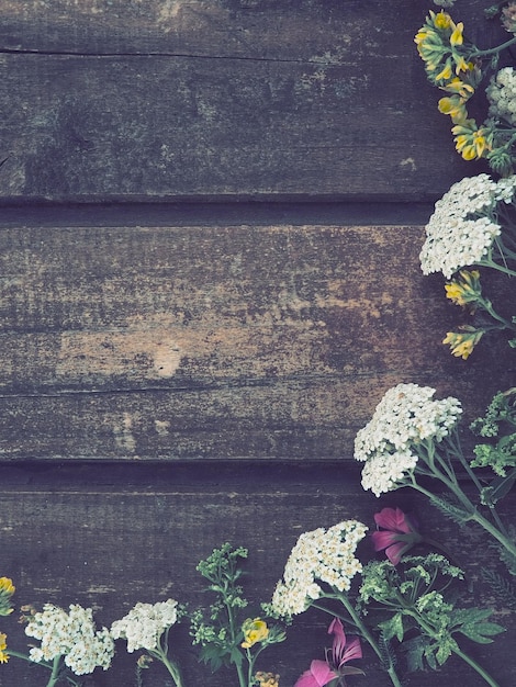 Veelkleurige wilde bloemen zijn gerangschikt in een halve cirkel op een houten tafel achtergrond Witte duizendblad bloeiwijzen geel gras muis erwten roze klimop geranium Horizontale planken Romantische Provençaalse stijl