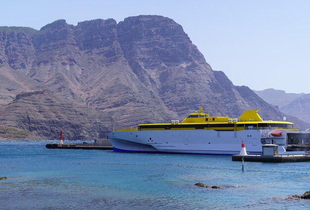 Veerboot aangemeerd in de haven naast een enorme berg aan zee, het landschap van Gran Canaria. Europa,