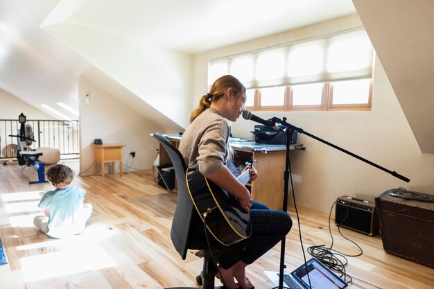 Veertien jaar oud tienermeisje dat haar gitaar speelt en haar broer op de achtergrond zingt