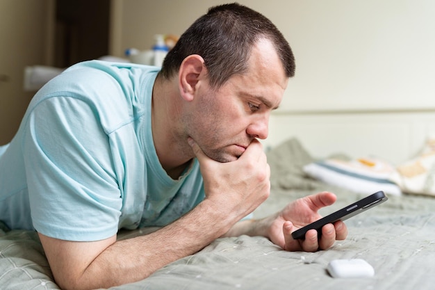 Veertig jaar oude man met smartphone thuis scrollen typen lezen nieuws sociaal internet activiteit leven met gadget