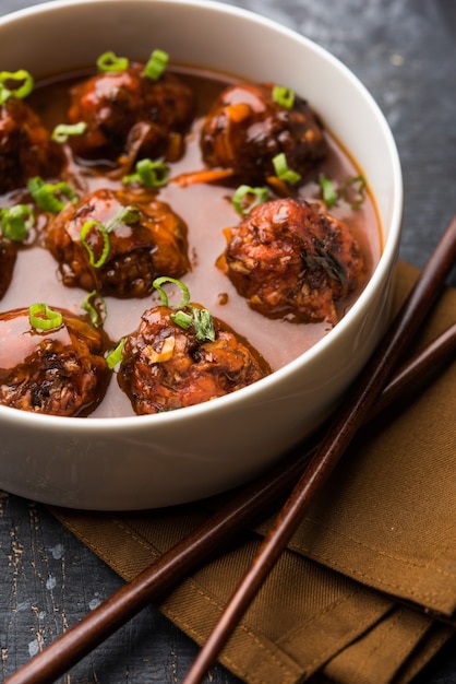 Veg or chicken Manchurian with gravy - Popular food of India served in a bowl with chopstick