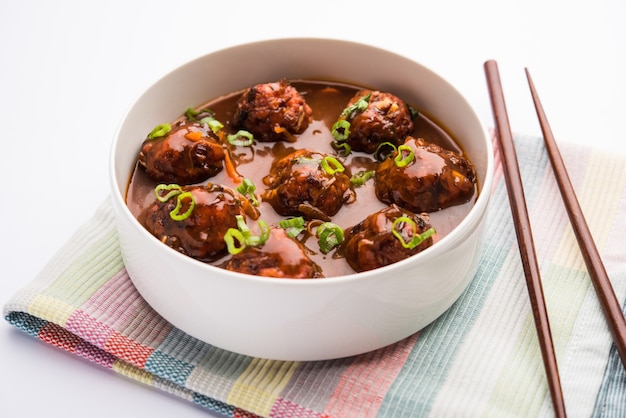 사진 그레이비를 곁들인 야채 또는 닭고기 만주 - 젓가락으로 그릇에 제공되는 인도의 인기 있는 음식
