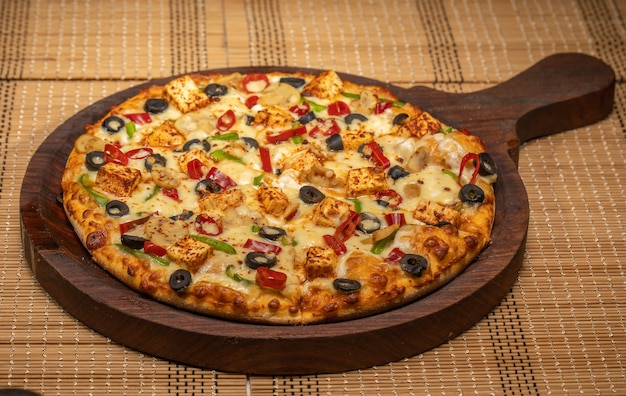 Veg Pizza on wooden pizza board, isolated over a rustic wooden background, selective focus