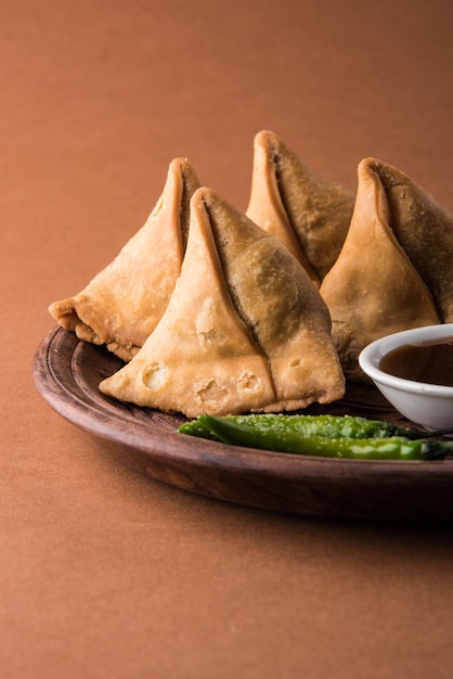 Veg Samosa - is a crispy and spicy Indian triangle shape tea time snack Served with fried green chilly, onion &amp; chutney or ketchup