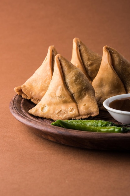 Veg Samosa - 파삭 파삭하고 매운 인도 삼각형 모양의 티 타임 스낵으로 튀긴 녹색 고추, 양파 및 처트니 또는 케첩과 함께 제공됩니다.