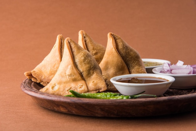 Veg Samosa - is a crispy and spicy Indian triangle shape tea time snack Served with fried green chilly, onion &amp; chutney or ketchup