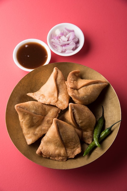 Veg samosa - è uno snack indiano croccante e speziato a forma di triangolo per l'ora del tè servito con peperoncino verde fritto, cipolla e chutney o ketchup