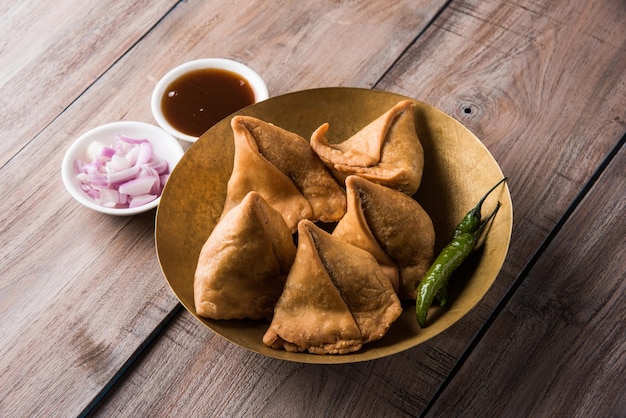 Veg Samosa - is a crispy and spicy Indian triangle shape tea time snack Served with fried green chilly, onion &amp; chutney or ketchup