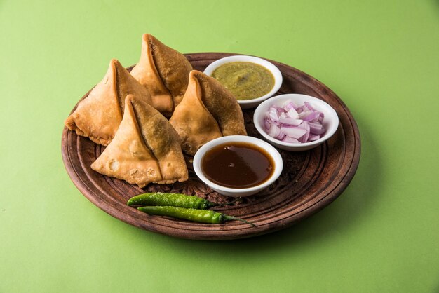 Veg Samosa - is een knapperige en pittige Indiase driehoekige theetijdsnack. Geserveerd met gebakken groene peper, ui & chutney of ketchup