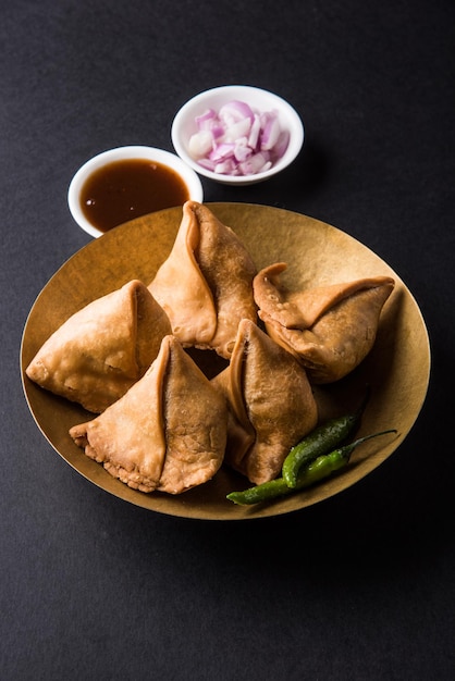 Veg Samosa - is een knapperige en pittige Indiase driehoekige theetijdsnack. Geserveerd met gebakken groene peper, ui & chutney of ketchup