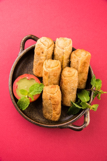 Photo veg spring rolls with mint leaf and green chutney or tomato ketchup. selective focus