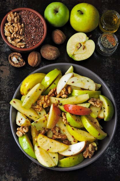 Vegan appel salade in een kom. Gezonde salade met appels, walnoten, kruiden en lijnzaad. Handige herfst appel- en notensalade.